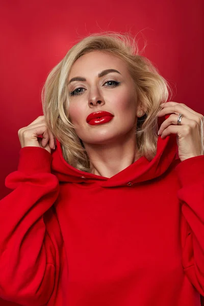 Stijlvolle mode blonde vrouw op rode achtergrond. — Stockfoto