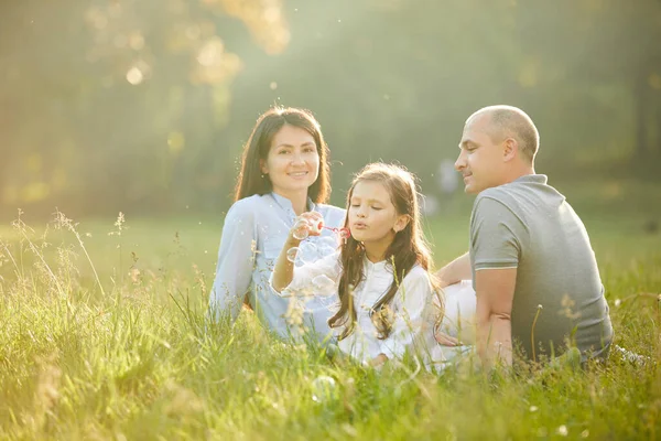 Happy family with child girl blow soap bubbles — Stock Photo, Image
