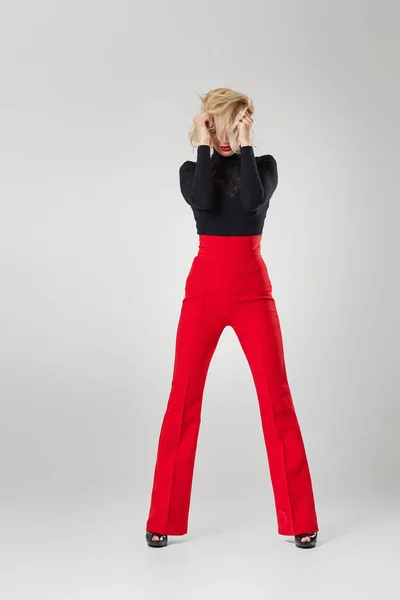 blonde woman in black shirt and red pants