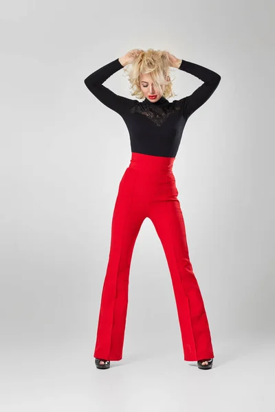 blonde woman in black shirt and red pants