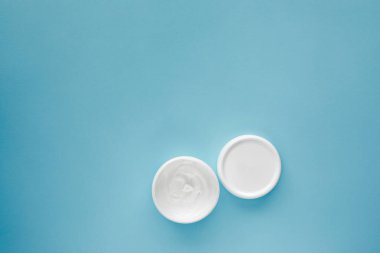 Mavi arkaplanda boş kozmetik kavanozu.