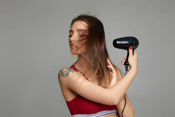 young woman drying her hair with dryer