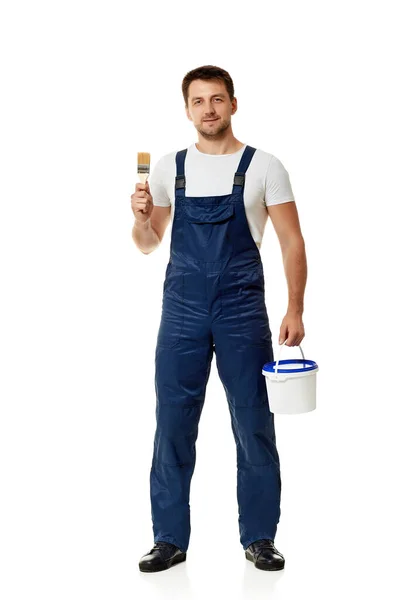 Repairman in blue uniform holding paint brush and can with paint — Stock Photo, Image