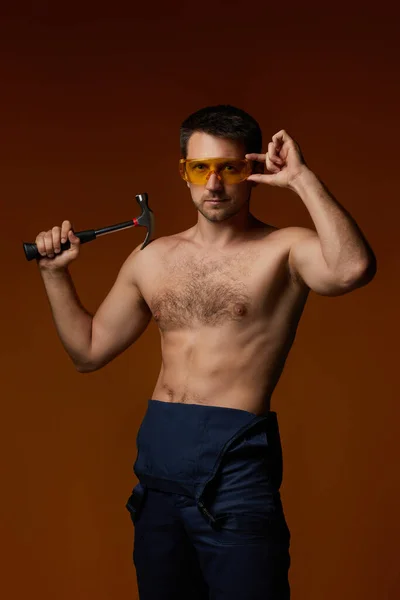 Sexy caucásico hombre trabajador en uniforme holding hammer — Foto de Stock