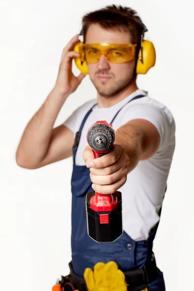 Reparador em uniforme, óculos de segurança e fones de ouvido com chave de fenda sem fio . — Fotografia de Stock