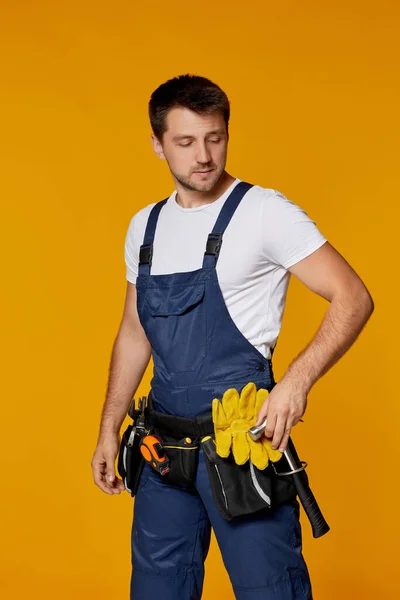 Operaio riparatore in cappello rigido giallo e martello uniforme. — Foto Stock