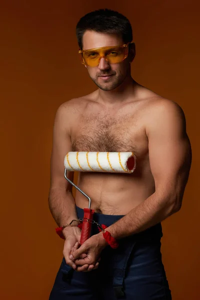 Sexy caucasico uomo lavoratore ammanettato tenendo vernice rotolo — Foto Stock