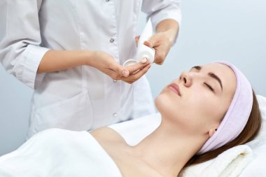 Güzellik uzmanı maskesini kadının yüzüne takıyor.