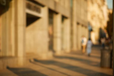 Şehrin güneşli sokaklarında yürüyen insanlar.