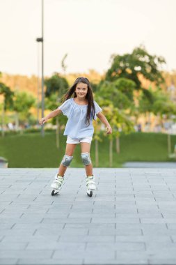 Küçük kız yaz parkında paten kayıyor..