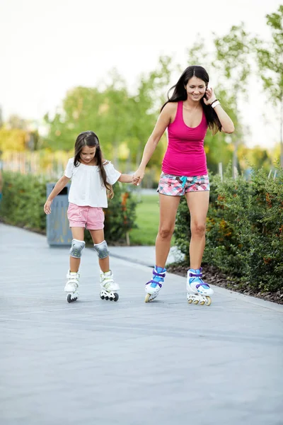 Young mother and her little daughter rollerskating — Stock Photo, Image
