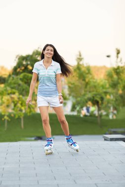 Gülümseyen genç kadın paten kayıyor.