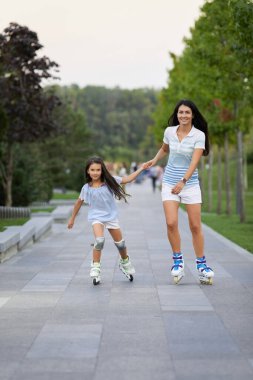 Anne ve küçük kızı paten kayıyor.