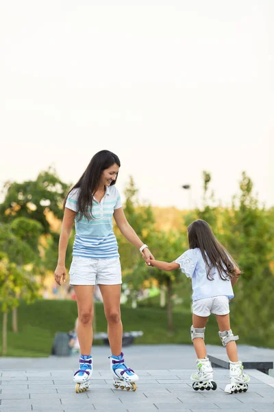 Young mother and her little daughter rollerskating — Stock Photo, Image