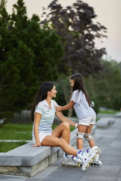 Happy little child girl and her mother are wearing roller skates — Stock Photo, Image