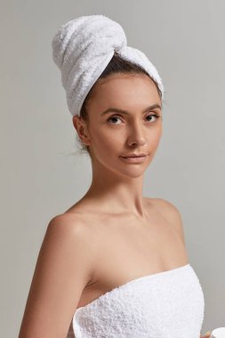 Esmer güzel kadın beyaz havlu giyiyor.