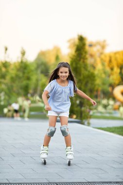 Küçük kız yaz parkında paten kayıyor..
