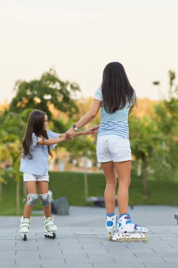 Genç anne ve küçük kızı paten kayıyor.