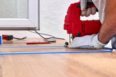 Elektrikli yapboz kullanan ve mutfak tezgahındaki lavabo için delik açan bir tamirci.