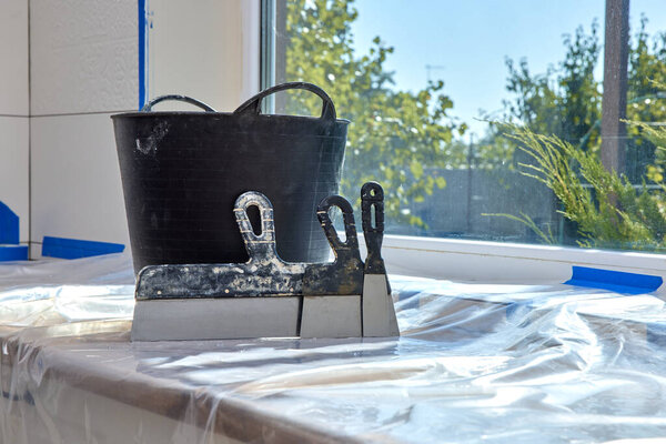 wall repair tools. Kit of putty knives and plaster bucket on kitchen countertop. renovation work