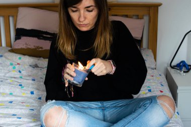 Genç ve çekici bir kadının yatağında mum yakarken çekilmiş fotoğrafı..