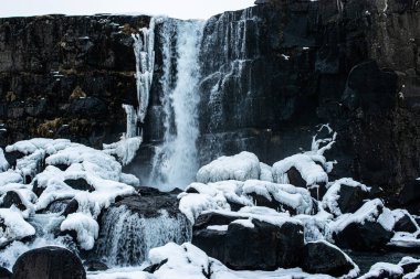 İzlanda 'da karla çevrili etkileyici bir çağlayanın fotoğrafı.