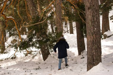 Sırtında kışlık paltosu ve ormanda karda yürüyen şapkası olan çekici bir adamın fotoğrafı..