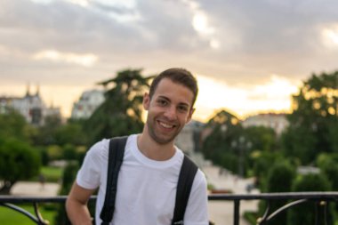 Doğanın ortasında duran sırt çantalı genç ve çekici bir adamın fotoğrafı.