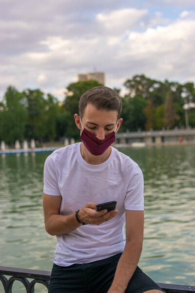 Photo of a young and attractive man talking on the phone and wearing a white t-shirt