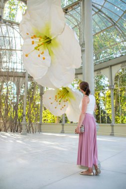 Madrid, Spain / August 7th 2020: Photo of a young and attractive woman visiting a flower exhibition inside the Cristal Palace in Madrid during summer wearing a face mask clipart