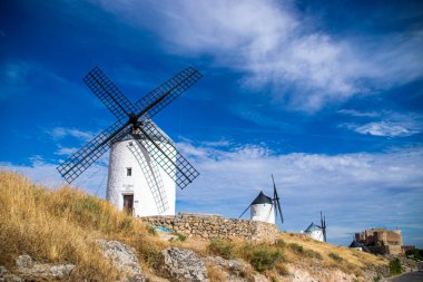 Güneşli bir yaz gününde İspanya 'nın Consuegra kentindeki bazı güzel ve tarihi yel değirmenlerinin fotoğrafı.. 