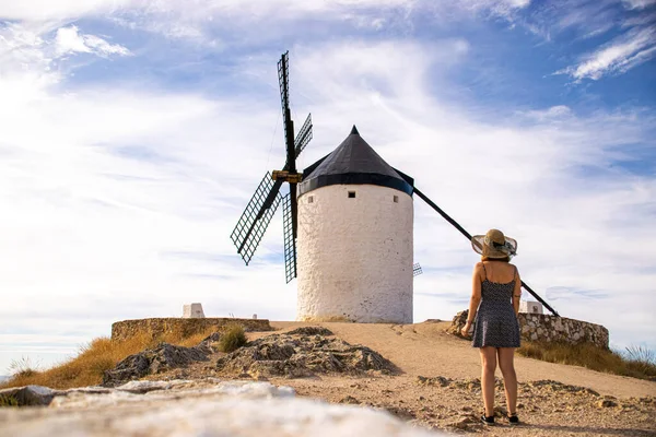 Güneşli bir yaz gününde İspanya, Consuegra 'da bulunan güzel ve tarihi yel değirmenlerinin yanında duran çekici bir kadının fotoğrafı.. 