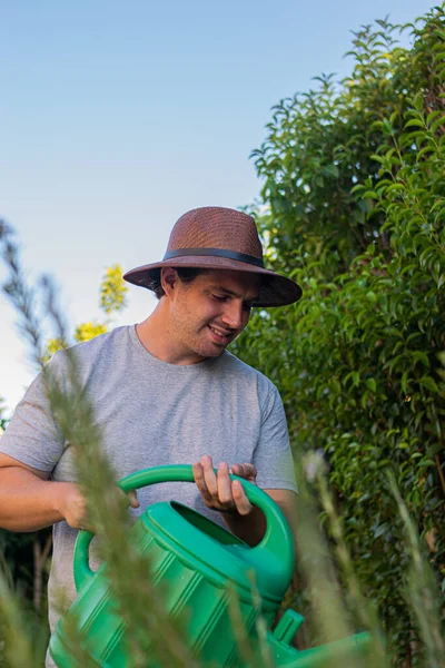 Foto Hombre Joven Atractivo Con Sombrero Marrón Regando Jardín Con —  Fotos de Stock