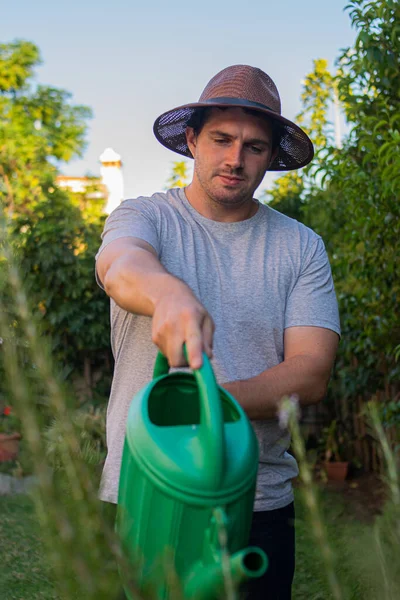 Foto Hombre Joven Atractivo Con Sombrero Marrón Regando Jardín Con —  Fotos de Stock