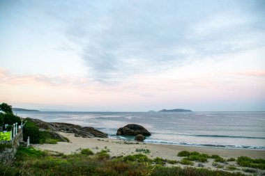 İspanya, Galiçya 'da yaz tatilinde kayaların ve deniz fenerinin fotoğrafı. Mavi okyanus, boş sahil.