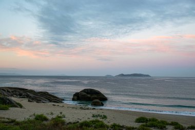 İspanya, Galiçya 'da yaz tatilinde kayaların ve deniz fenerinin fotoğrafı. Mavi okyanus, boş sahil.