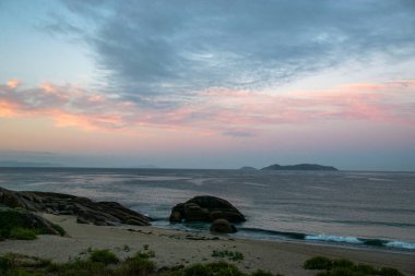İspanya, Galiçya 'da yaz tatilinde kayaların ve deniz fenerinin fotoğrafı. Mavi okyanus, boş sahil.