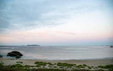 İspanya, Galiçya 'da yaz tatilinde kayaların ve deniz fenerinin fotoğrafı. Mavi okyanus, boş sahil.