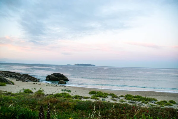 İspanya, Galiçya 'da yaz tatilinde kayaların ve deniz fenerinin fotoğrafı. Mavi okyanus, boş sahil.