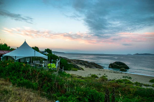 İspanya, Galiçya 'da yaz tatilinde kayaların ve deniz fenerinin fotoğrafı. Mavi okyanus, boş sahil.