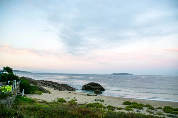İspanya, Galiçya 'da yaz tatilinde kayaların ve deniz fenerinin fotoğrafı. Mavi okyanus, boş sahil.