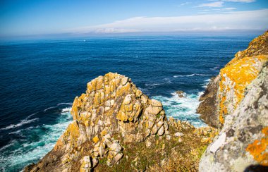 İspanya, Galiçya 'da yaz tatilinde kayaların ve deniz fenerinin fotoğrafı. Mavi okyanus, boş sahil.