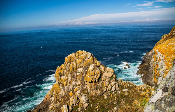İspanya, Galiçya 'da yaz tatilinde kayaların ve deniz fenerinin fotoğrafı. Mavi okyanus, boş sahil.