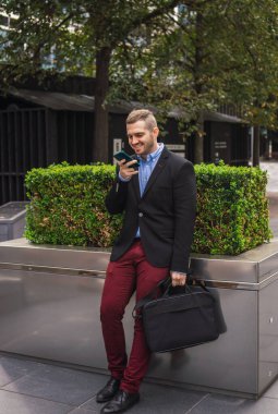 Genç ve çekici bir iş adamının şık günlük kıyafetler giyip iş molasında telefon görüşmesi yaptığı fotoğraf.