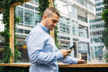 Genç ve çekici bir iş adamının bir görüşme ayarlamak için telefonda konuştuğu fotoğraf. Şık günlük giysiler giyiyor. 