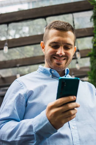 Photo of a young and attractive business man talking on the phone to fix a meeting. Wearing smart casual clothes