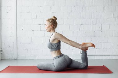 Spor yapan, yoga yapan, Vamadevasana yapan, Sage Vamadeva 'ya adanmış, gri spor giyim, stüdyo, tam boy
