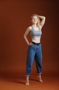 Kahverengi arka planda, yalnız ve doğal genç sarışın bir kadınla model testi.