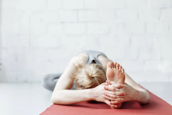 Koridorda yoga-asanas yapan genç bir kadın. Eka pada shirshasana. Pavirittu Jana Shirshasana. Genç sporcu, zayıf, sarışın kadın yoga koçu.