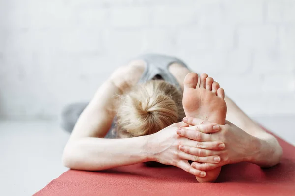 Koridorda yoga-asanas yapan genç bir kadın. Eka pada shirshasana. Pavirittu Jana Shirshasana. Genç sporcu, zayıf, sarışın kadın yoga koçu.